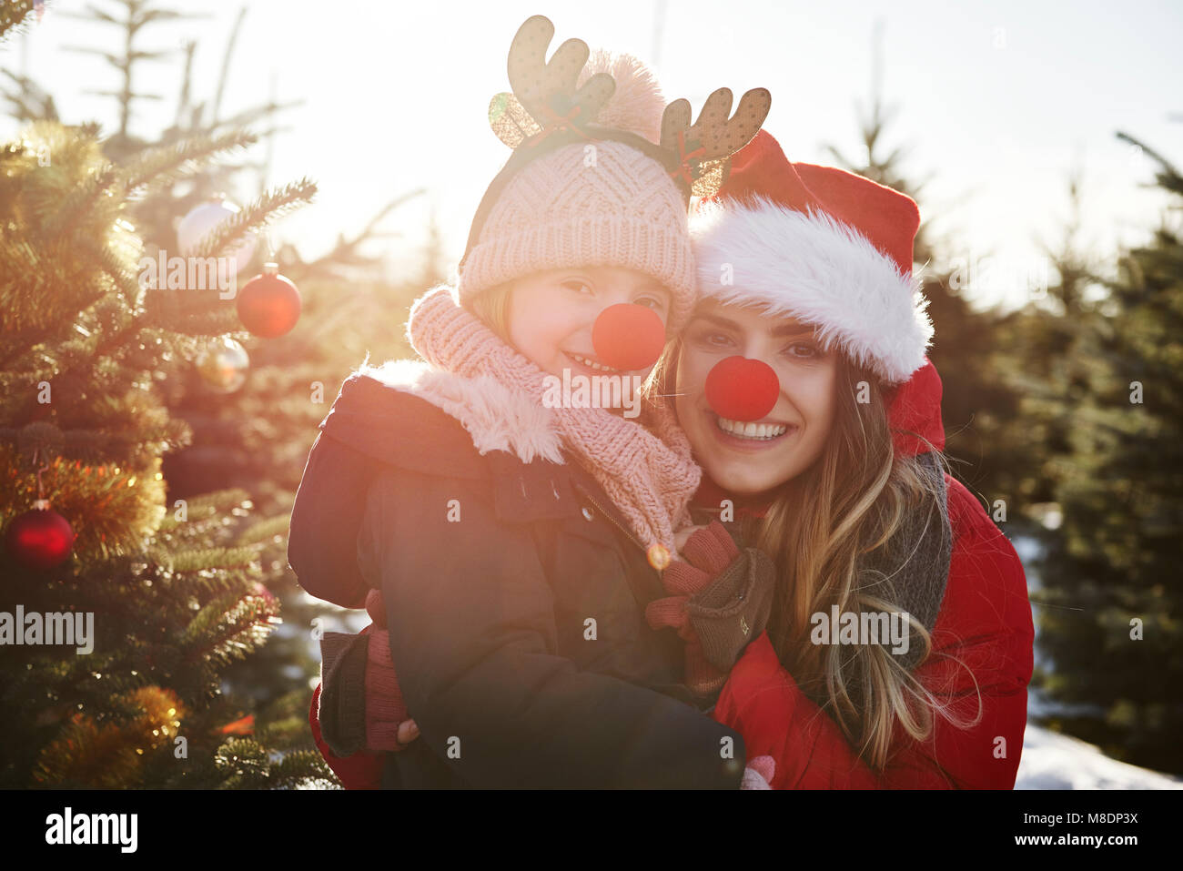 Girl and mother in christmas tree forest with red noses, portrait Stock Photo