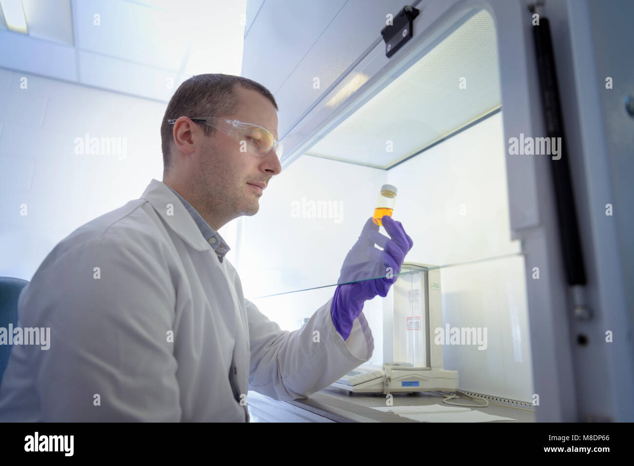 Scientist inspecting pharmaceutical sample in fume cupboard in laboratory Stock Photo