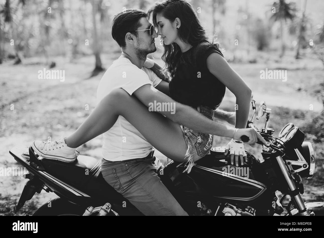 Young woman astride boyfriend on motorcycle, Krabi, Thailand, B&W Stock Photo