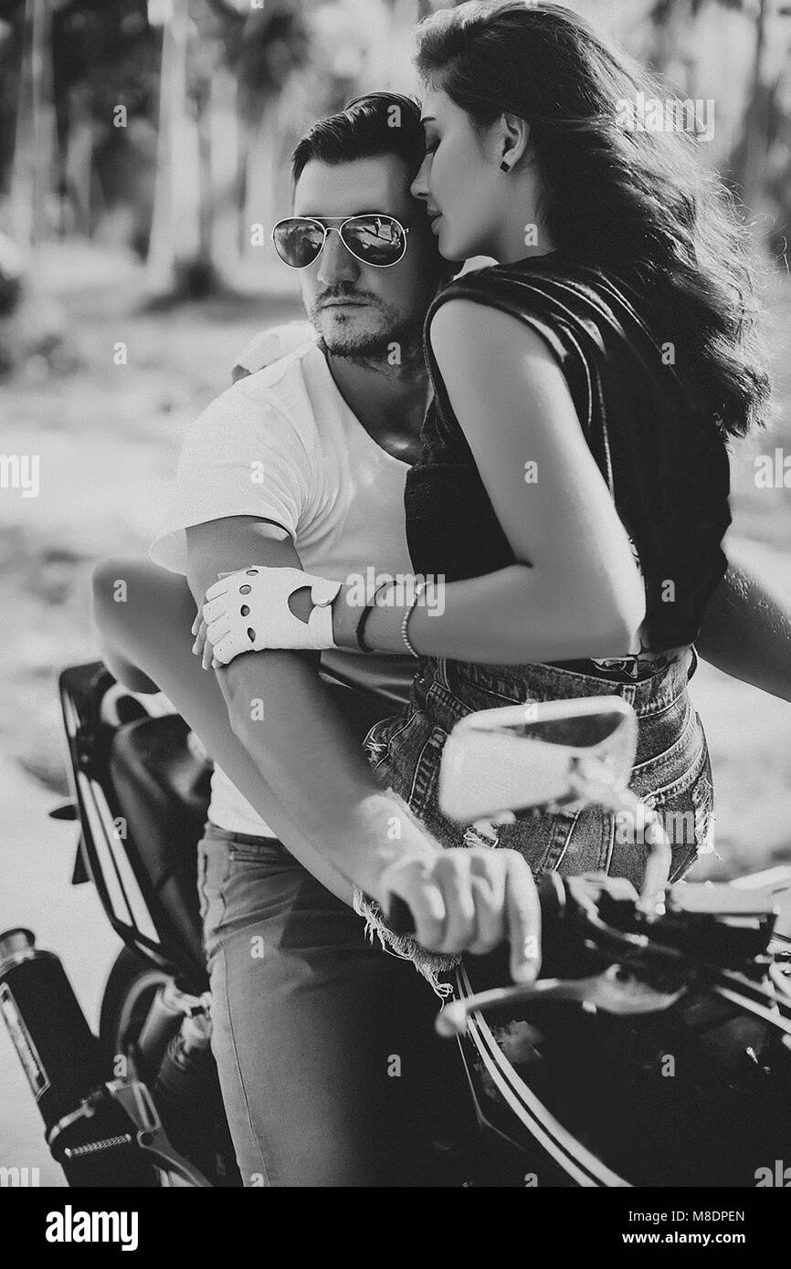 Young woman astride boyfriend on motorcycle, Krabi, Thailand, B&W Stock Photo
