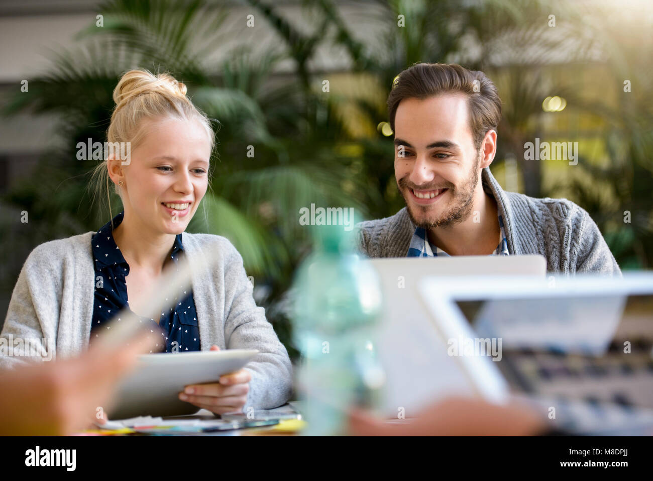 Male and female designer looking at laptop on design studio desk Stock Photo