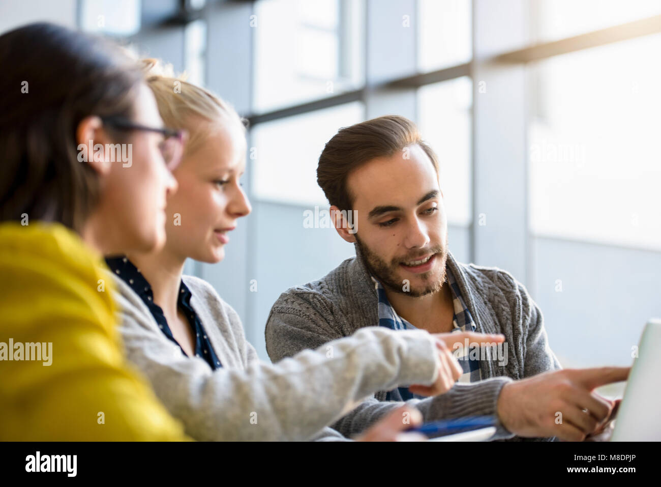Male and female designers pointing at laptop on design studio desk Stock Photo