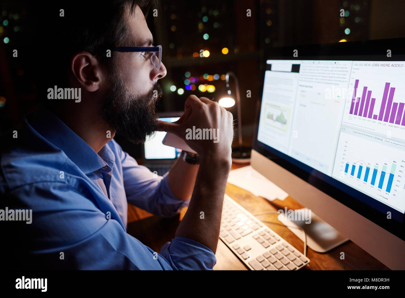 Young businessman looking at computer on office desk at night Stock Photo