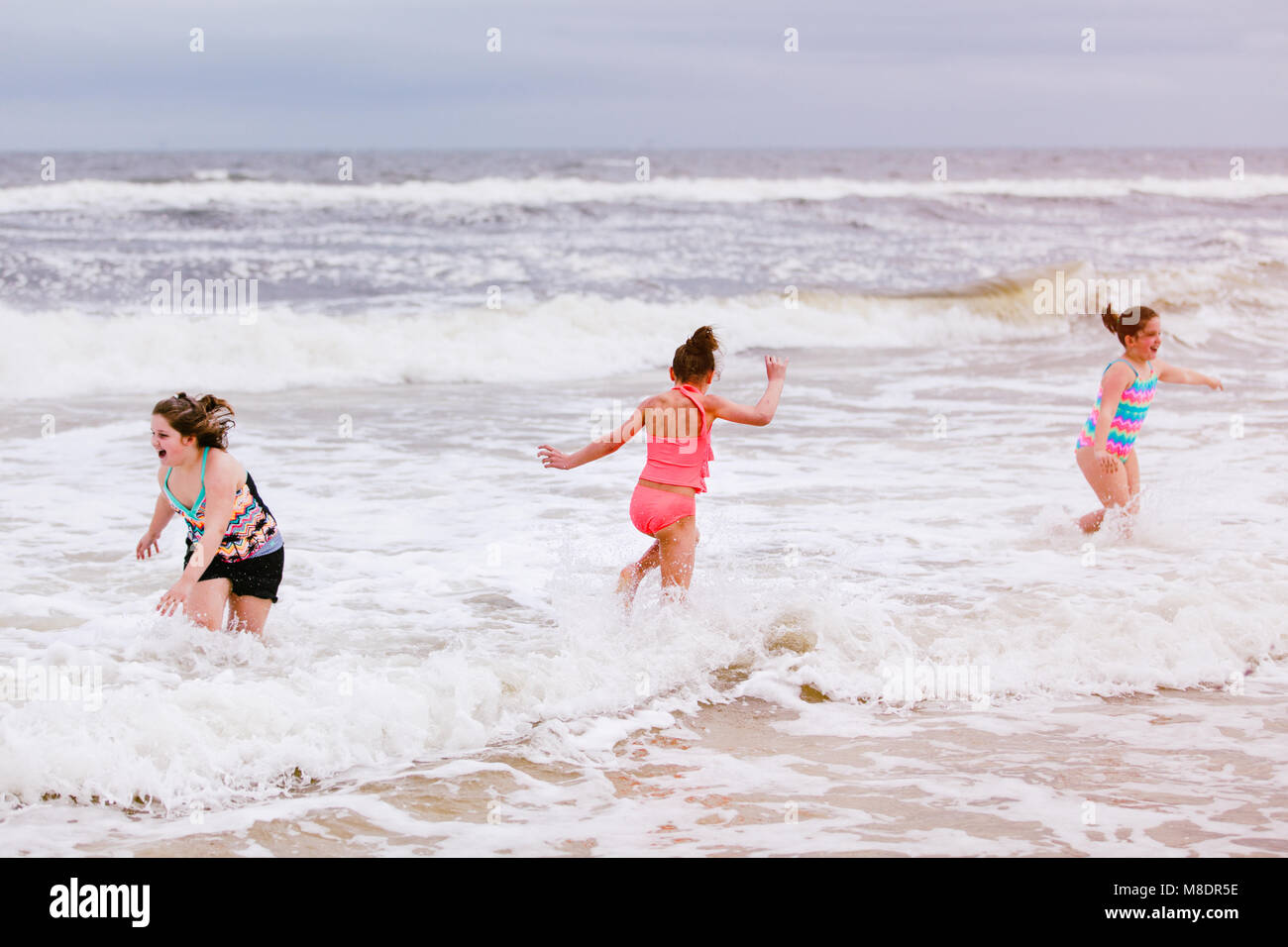 Three girls playing in ocean waves, Dauphin Island, Alabama, USA Stock Photo