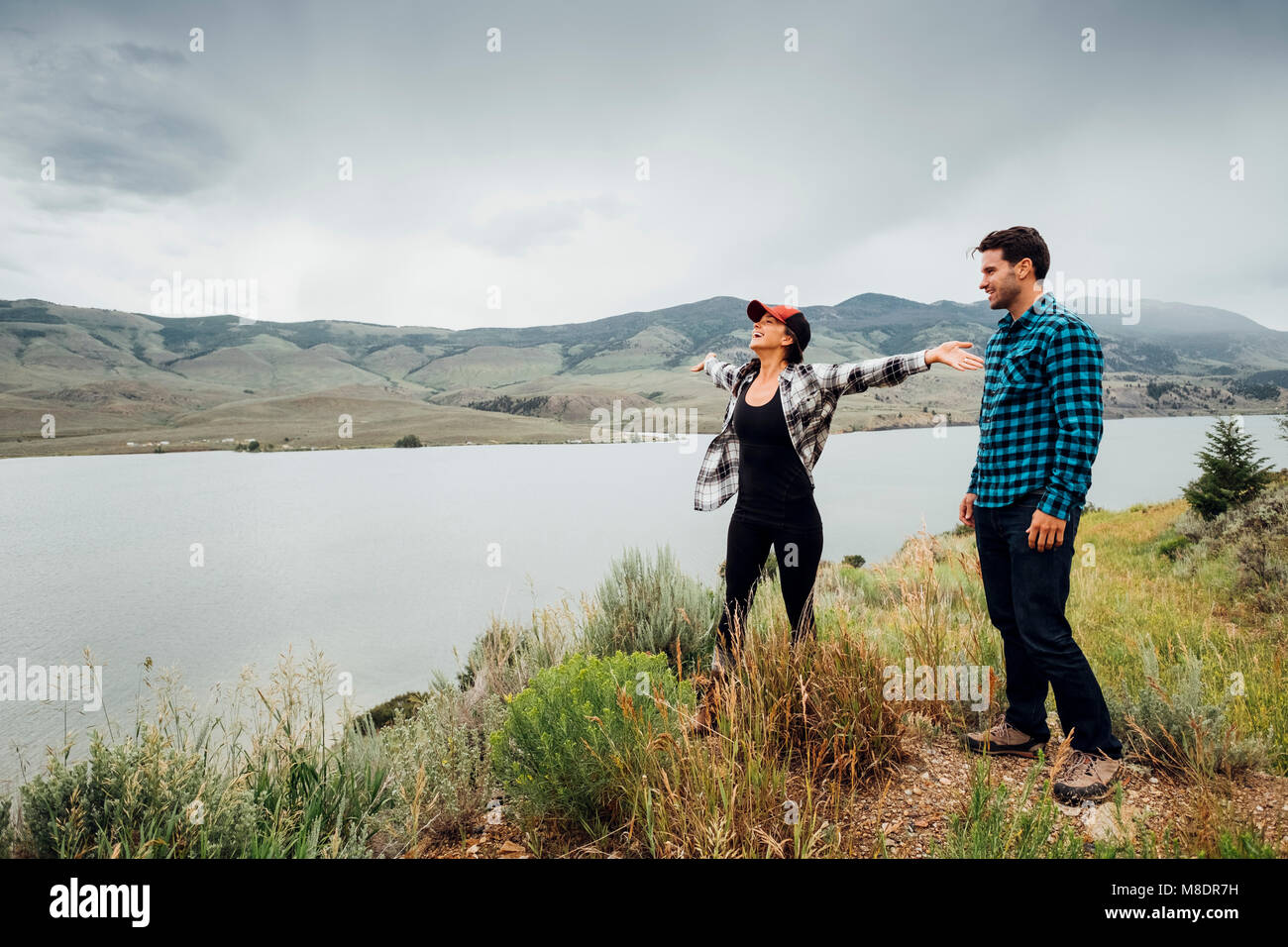 Couple walking near Dillon Reservoir, young woman's arms outstretched, Silverthorne, Colorado, USA Stock Photo