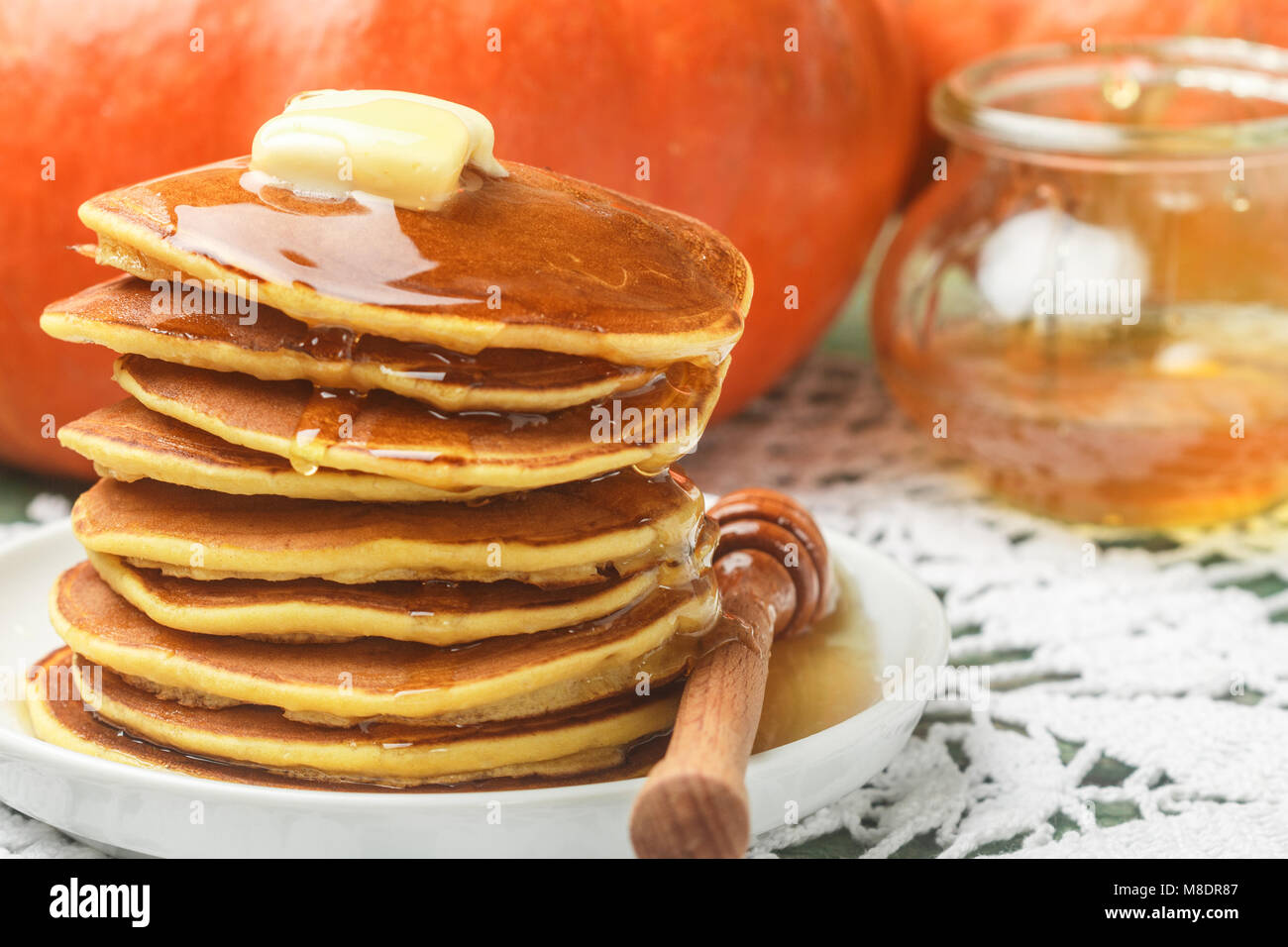 Homemade pumpkin pancakes with butter and honey on a white plate on the table. Useful, tasty Breakfast. Selective focus Stock Photo