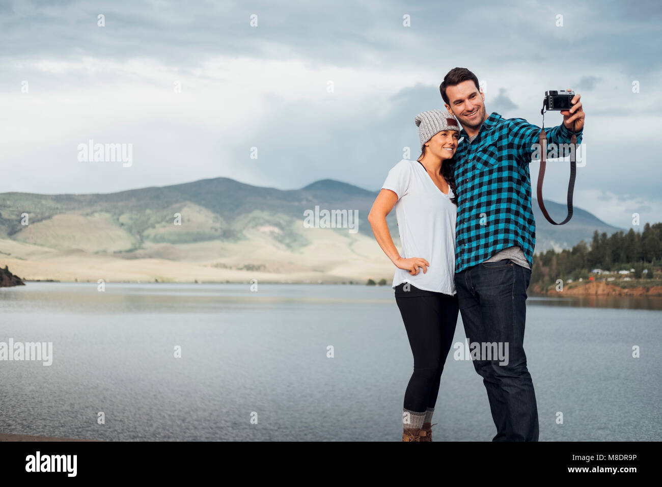 Couple beside Dillon Reservoir, taking selfie, using camera, Silverthorne, Colorado, USA Stock Photo