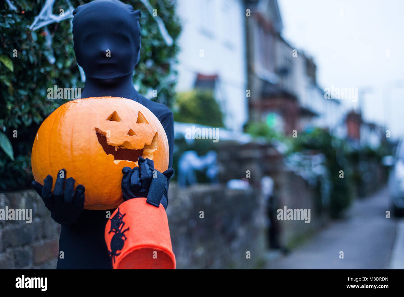 Portrait of boy in halloween costume, holding pumpkin and trick or treat bucket Stock Photo