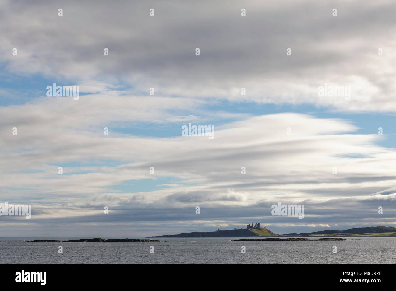 Dunstanburgh Castle and big skies Northumberland Stock Photo