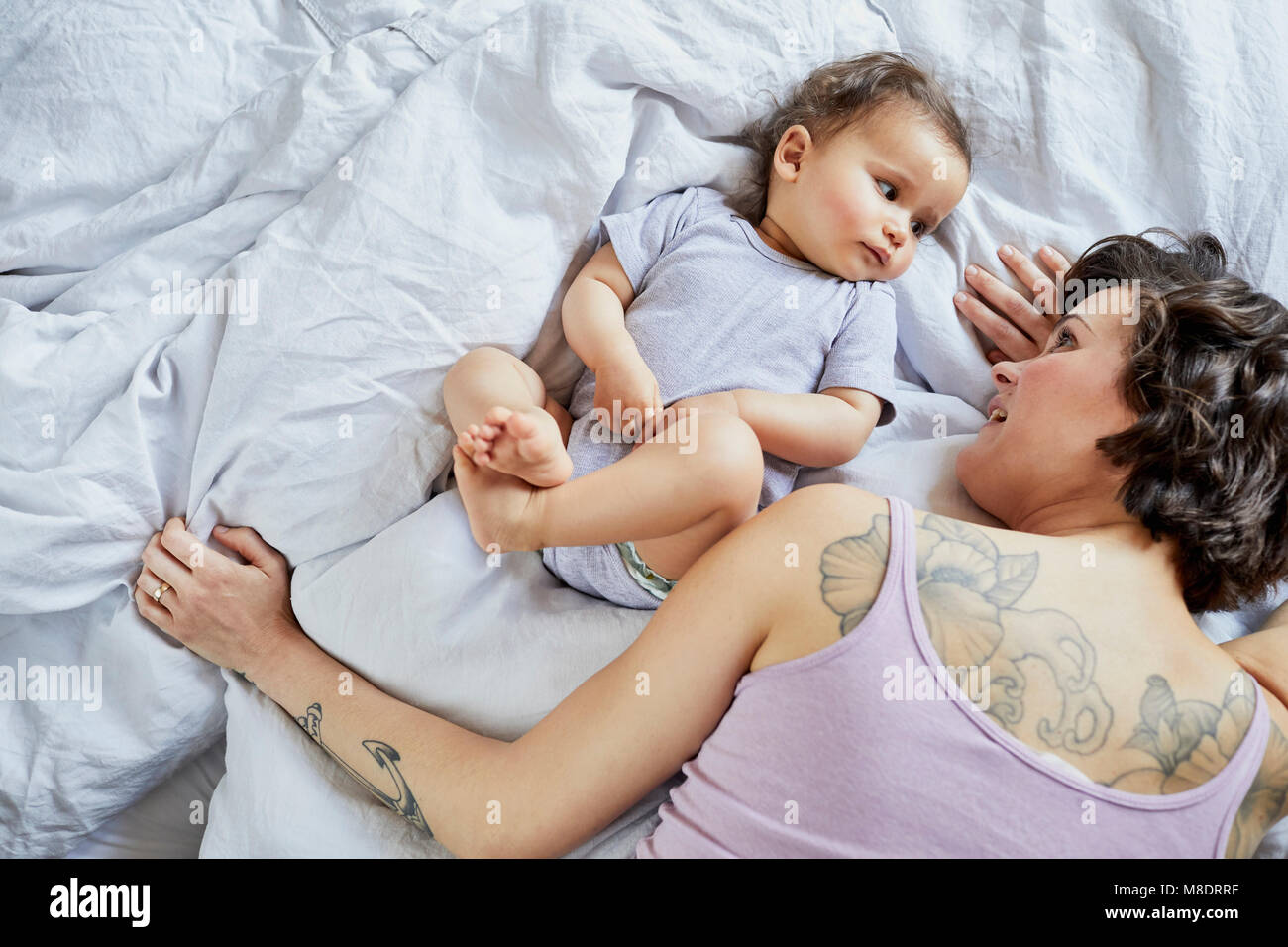 Mother and baby girl, lying on bed together Stock Photo