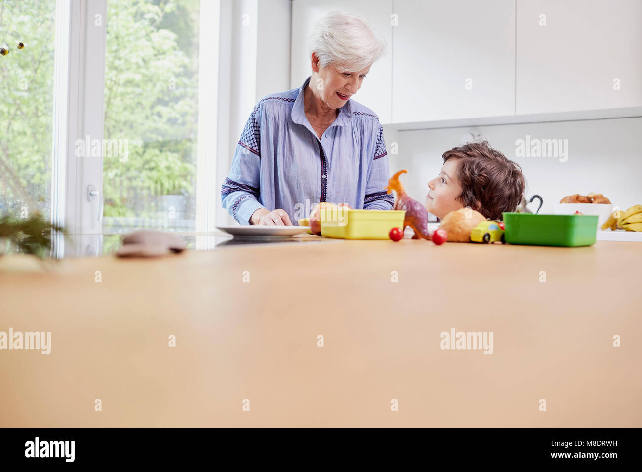 Grandmother and grandson preparing food in kitchen Stock Photo