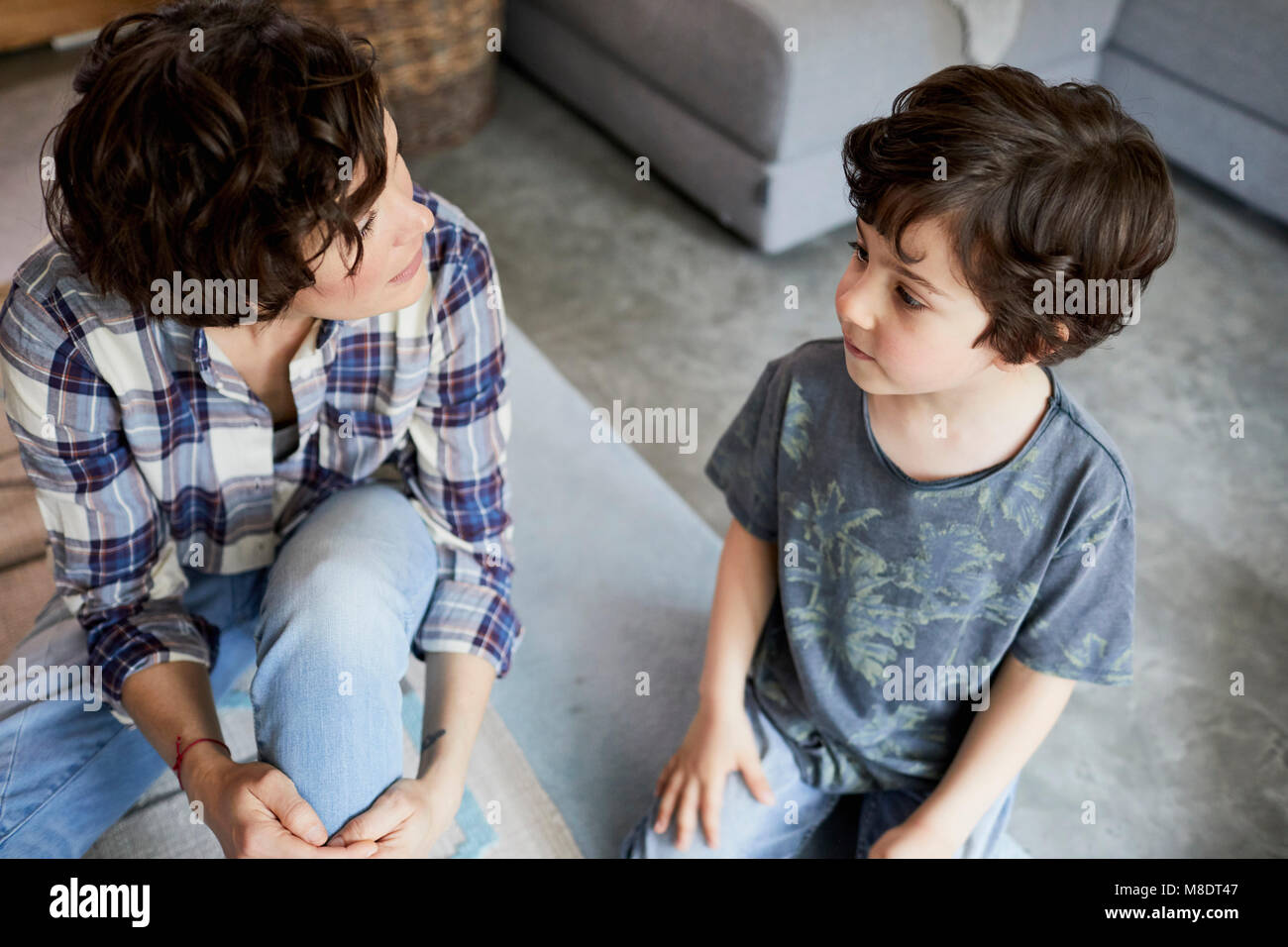Mother and son at home, sitting on floor, talking Stock Photo