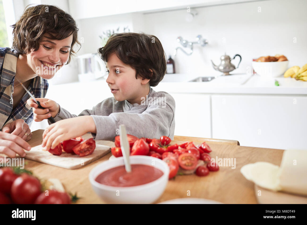 Mother and son preparing food in kitchen Stock Photo