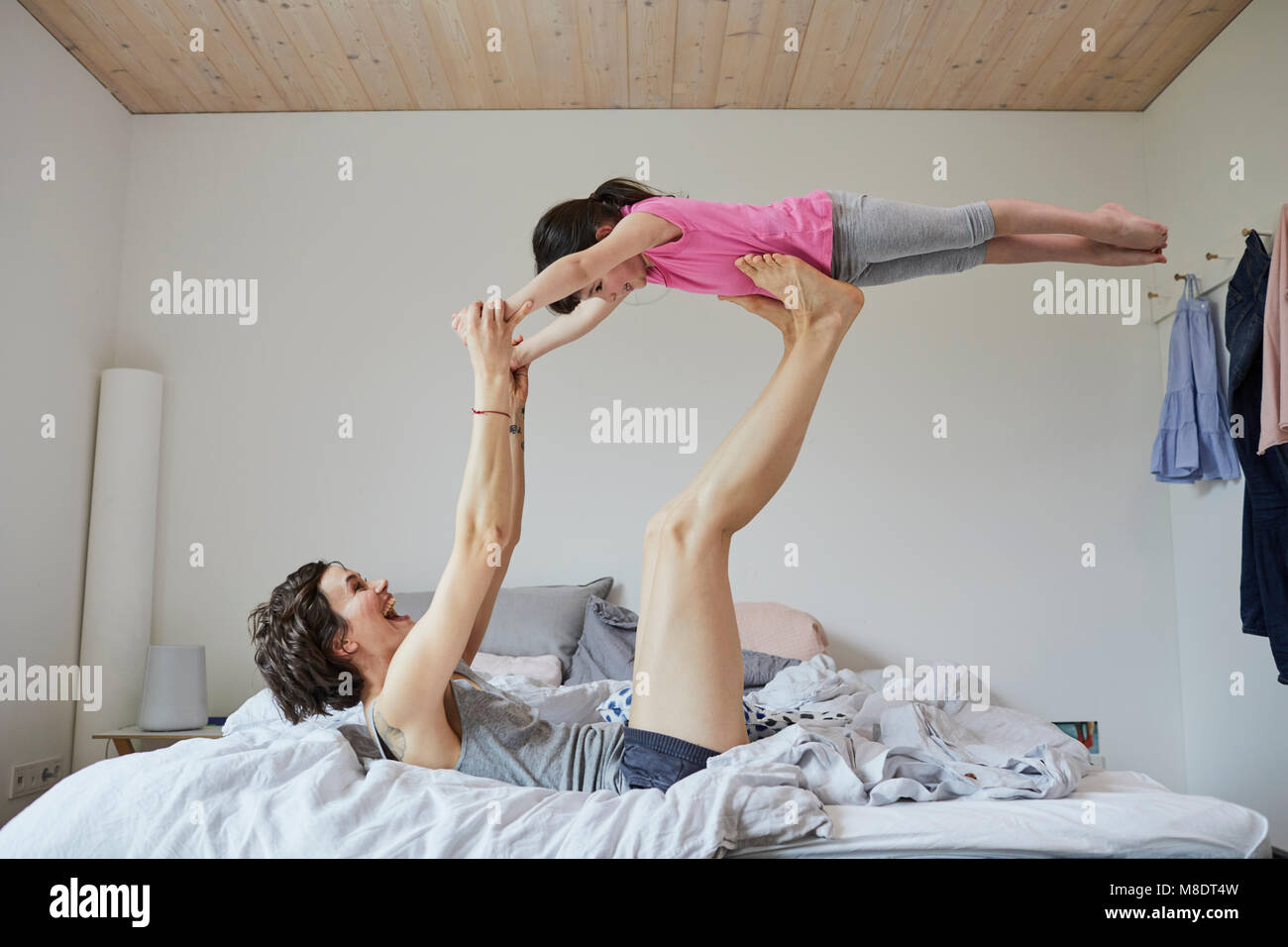Mother and daughter playing in bedroom, mother balancing daughter on feet Stock Photo