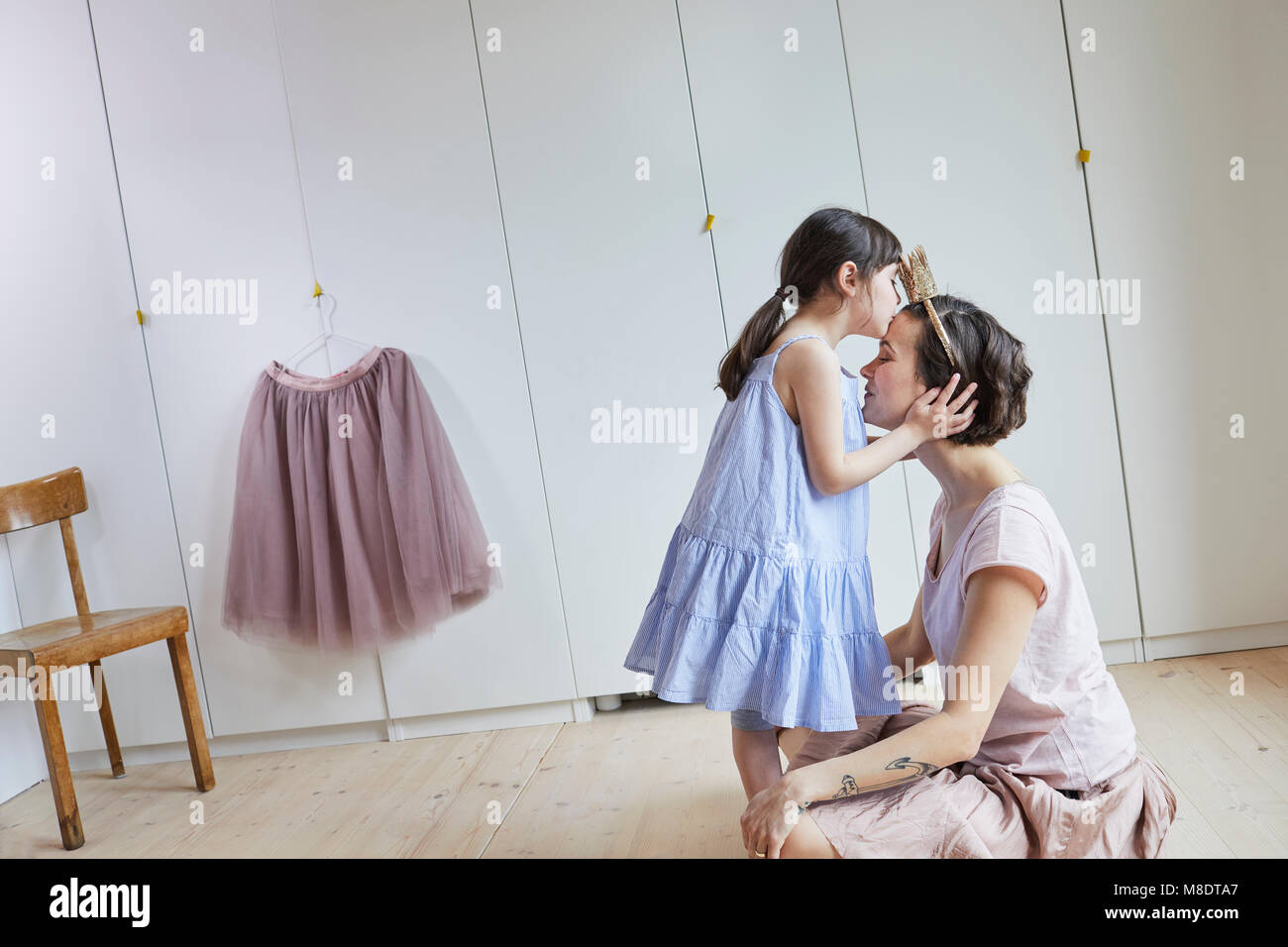 Mother and daughter in bedroom, face to face, daughter kissing mother on head Stock Photo