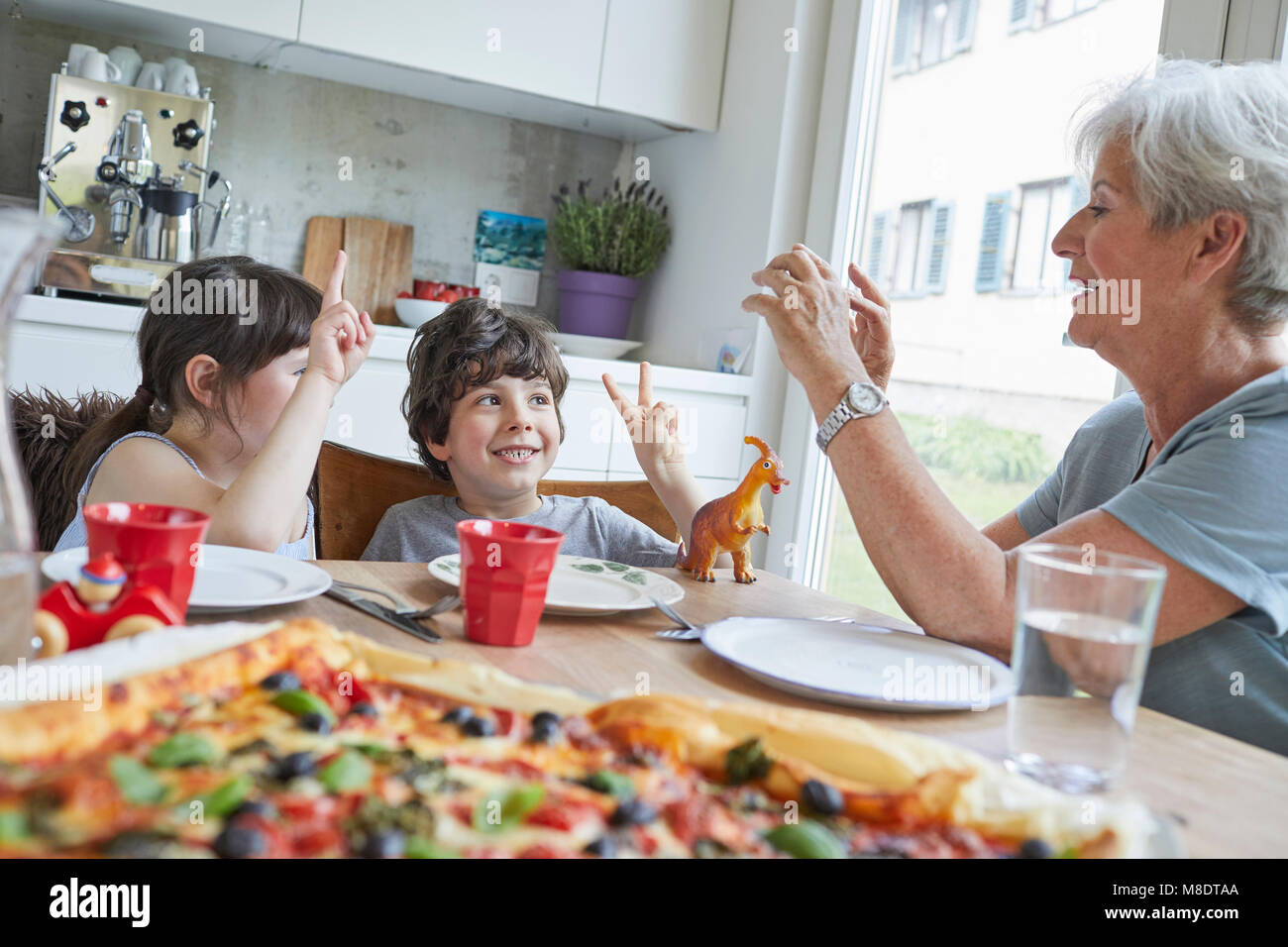 Grandmother and grandchildren sitting at table, grandmother photographing children Stock Photo