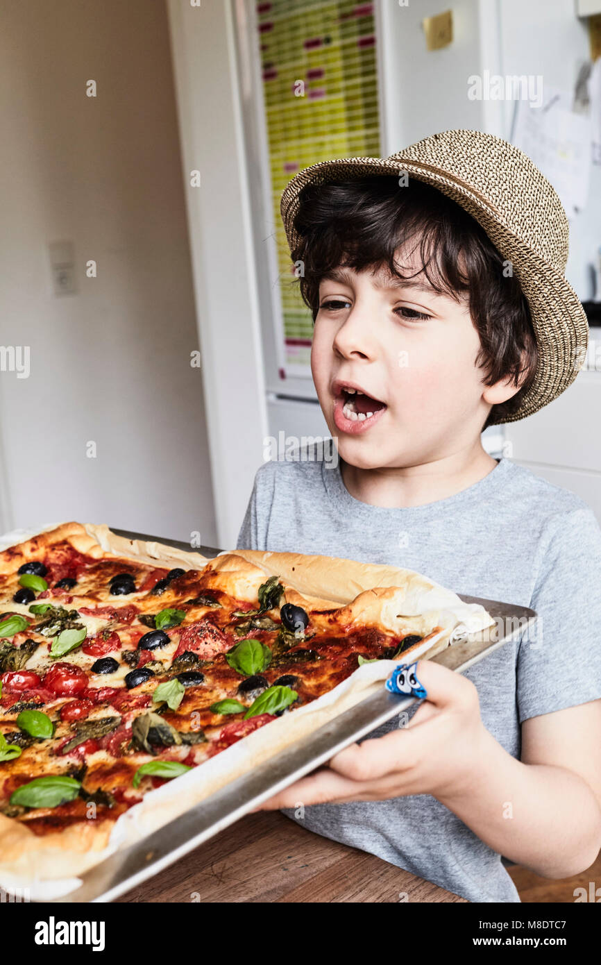 Young boy holding freshly baked pizza Stock Photo