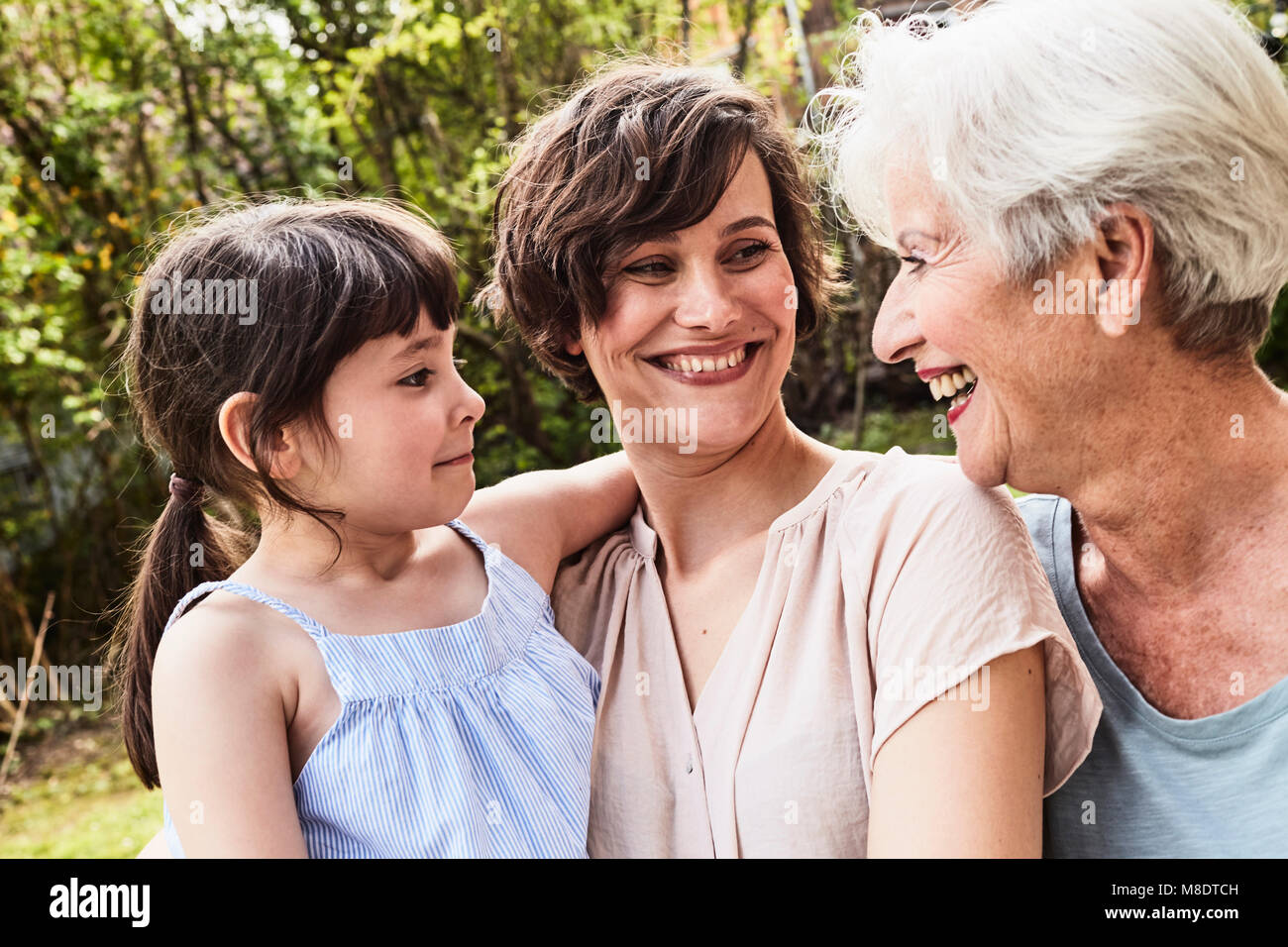 Portrait of senior woman with grown daughter and granddaughter, outdoors, smiling Stock Photo