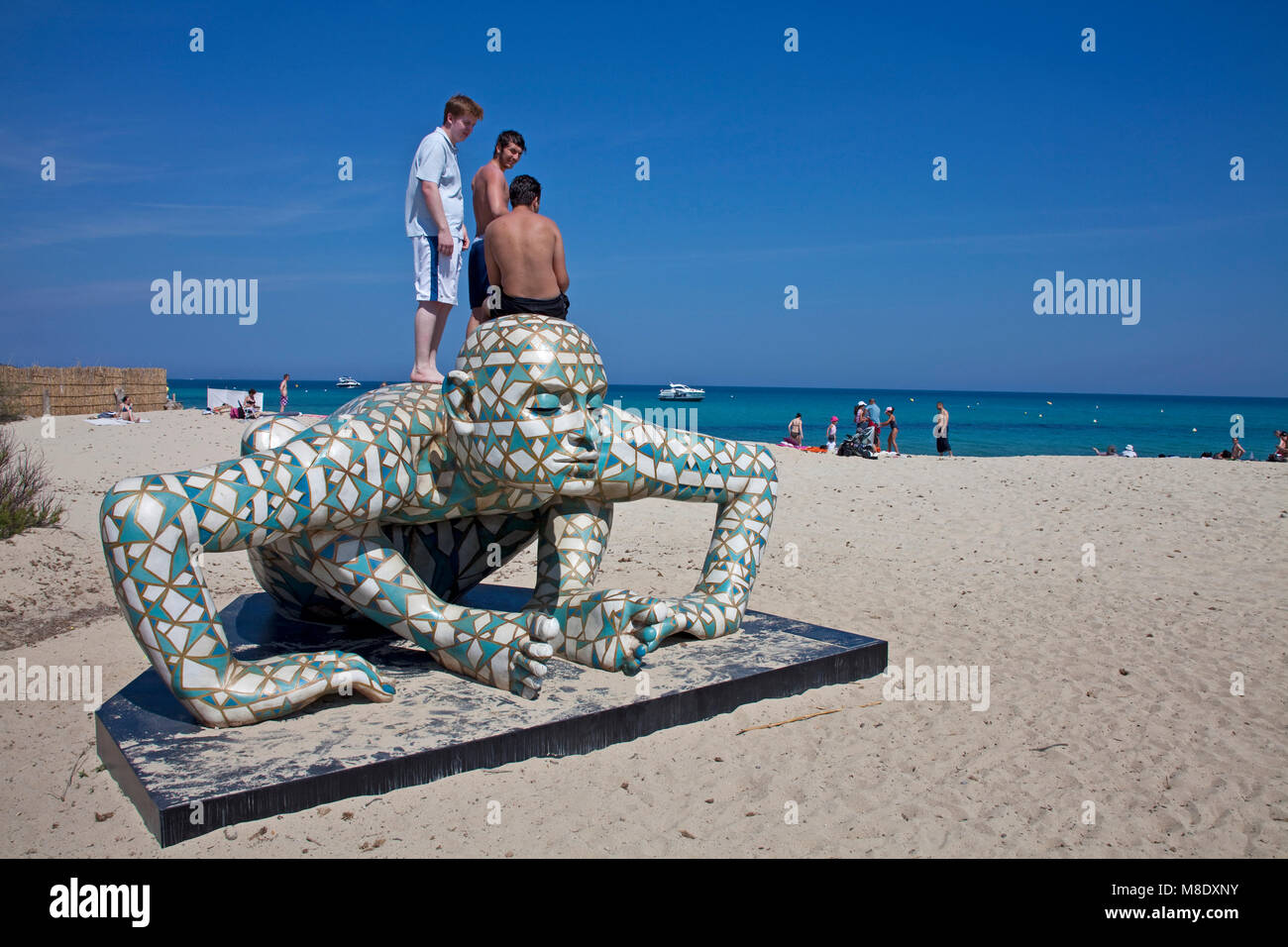 Young people standing on a Rabarama sculpture at Pampelonne beach, popular beach at Saint-Tropez, french riviera, South France, Cote d'Azur, France Stock Photo
