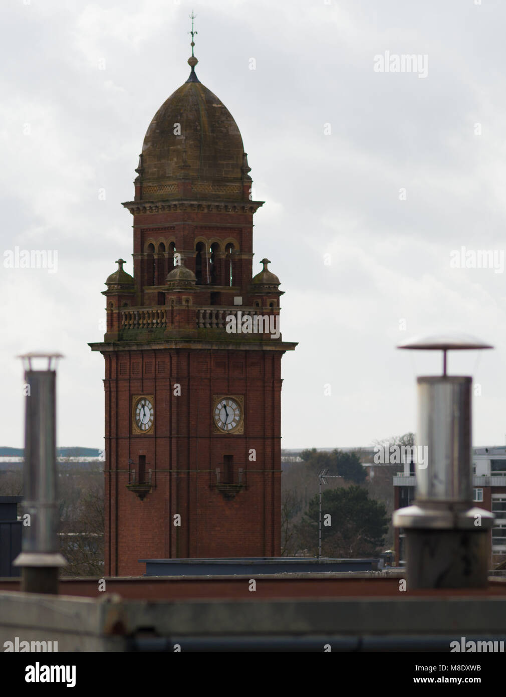 rooftop view of clock tower and metal chimney stacks in typical English