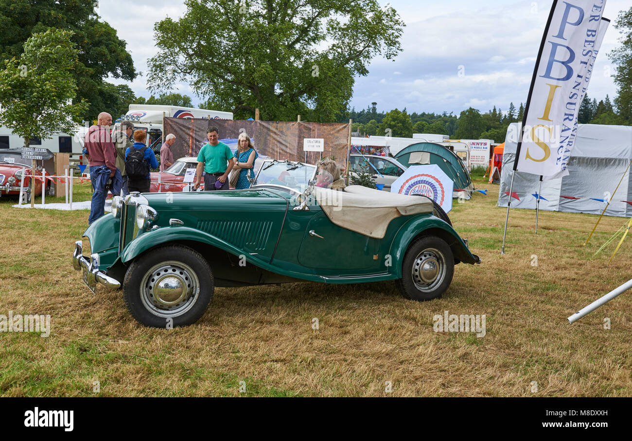 A Lady driving off in a vintage British Racing Green MG at the Strathmore Vintage Vehicle Extravaganza in Perthshire, Scotland. Stock Photo