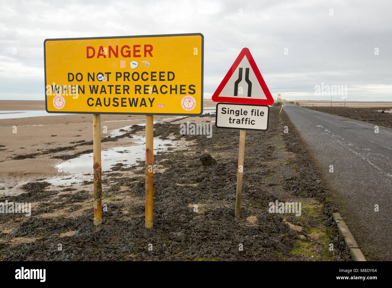 Warming signs about tidal flooding on the causeway to Holy Island, Northumberland, UK. Stock Photo