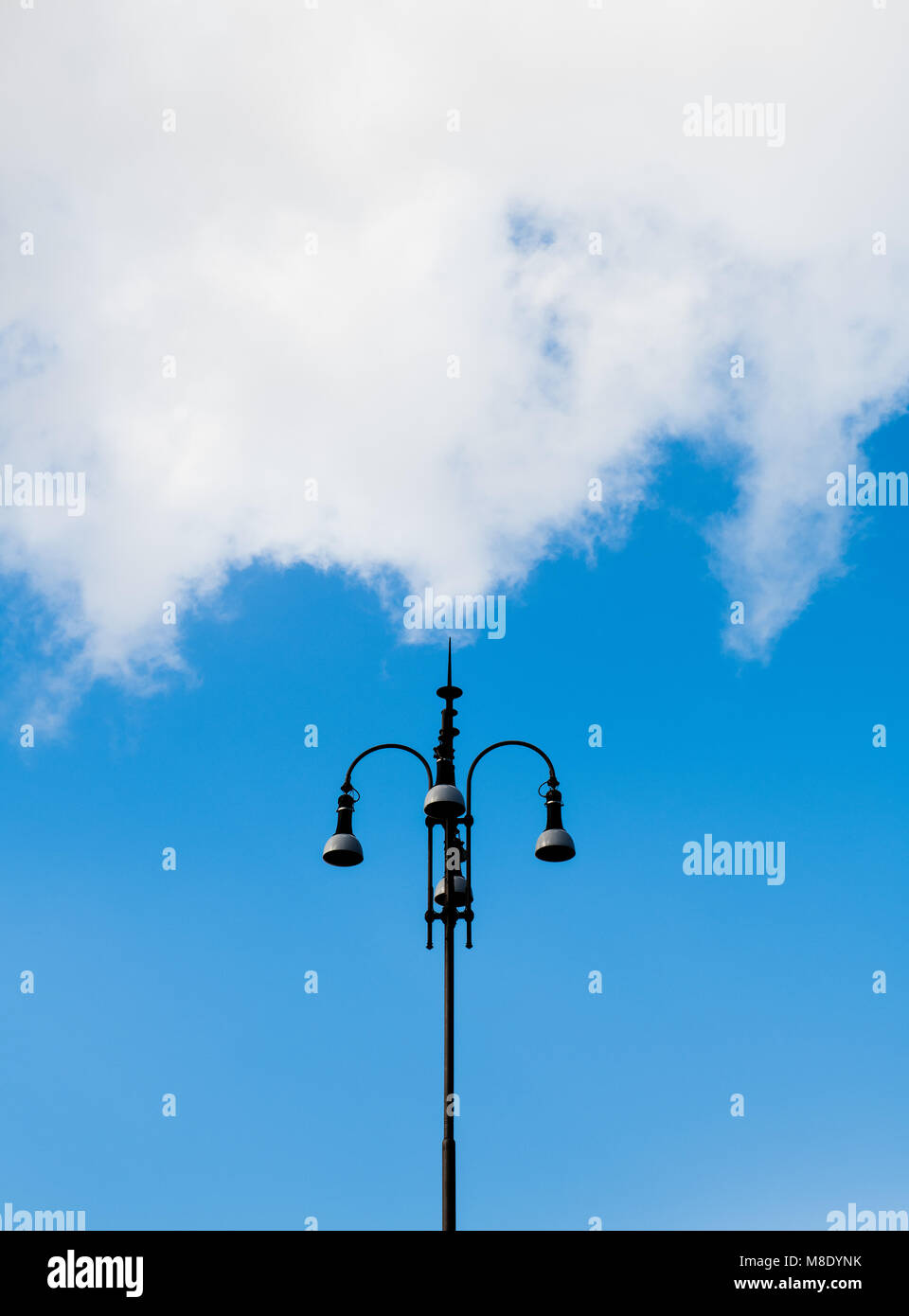 Retro european style urban light high streetlamp against blue sky and big white cloud Stock Photo