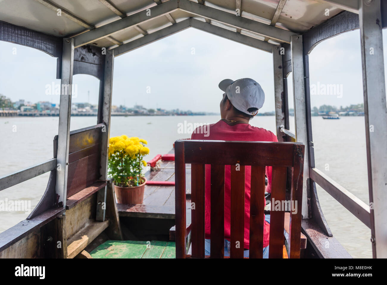 A tourist sits on a chair on one of the many tourist boats on the Meekong Delta, Vietnam Stock Photo