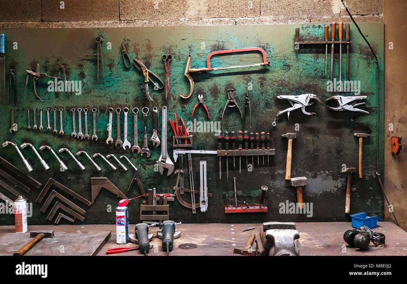 Wall with different metal instruments in little factory room ...