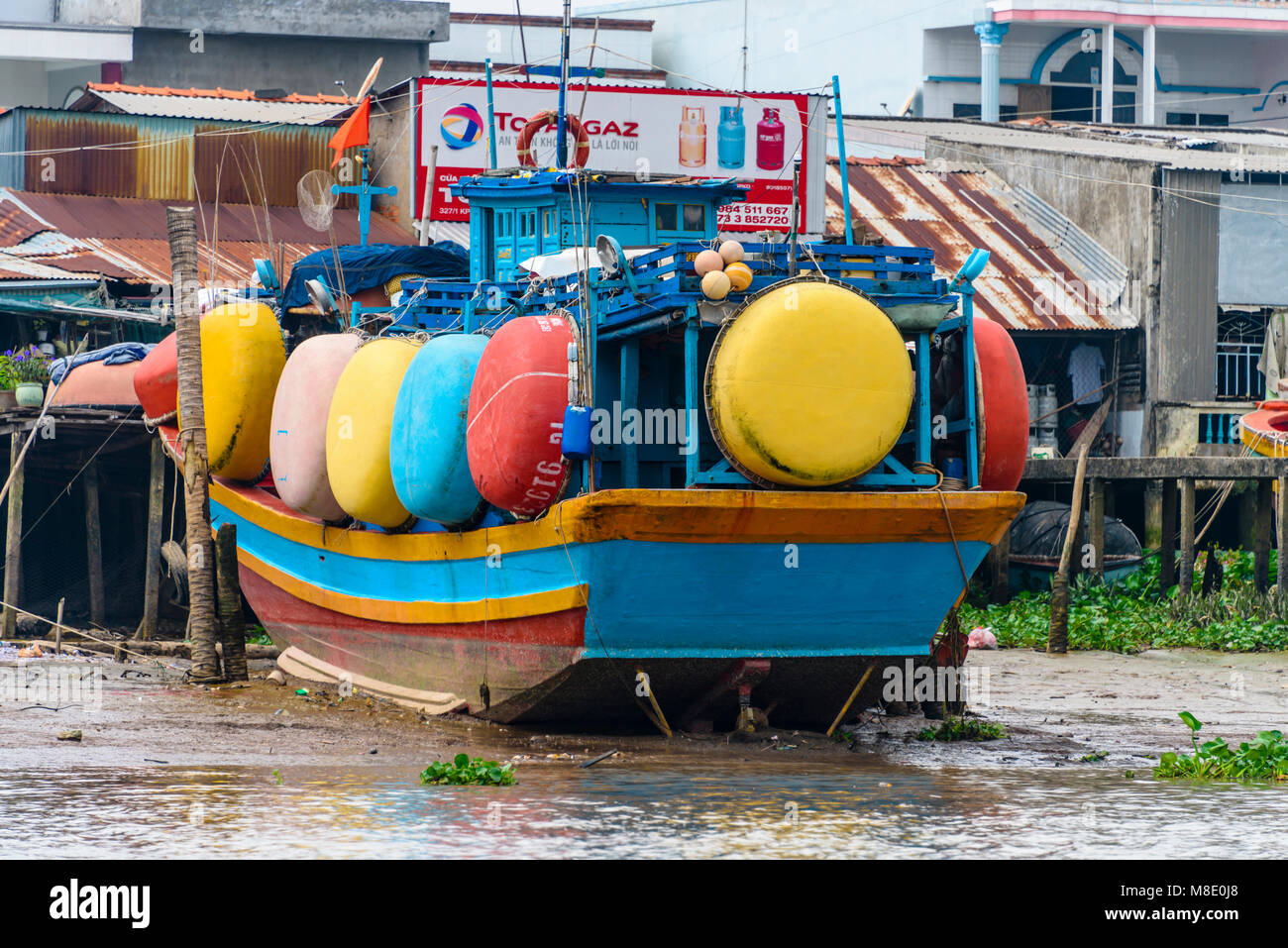 Colourful fishing coracles hung on the side of a wooden fishing boat on the bank of the Meekong River, Vietnam Stock Photo