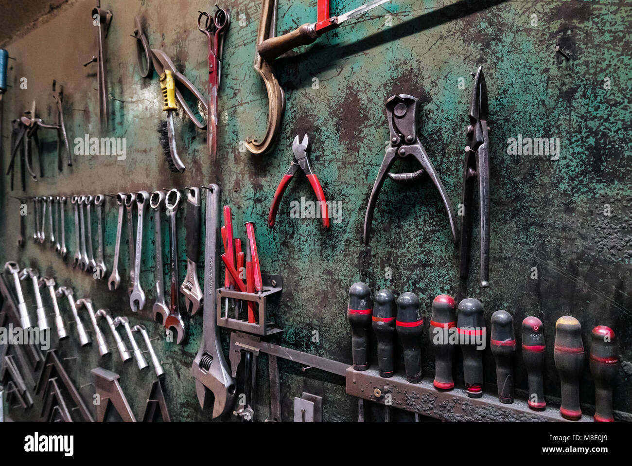Wall with different metal instruments in little factory room ...