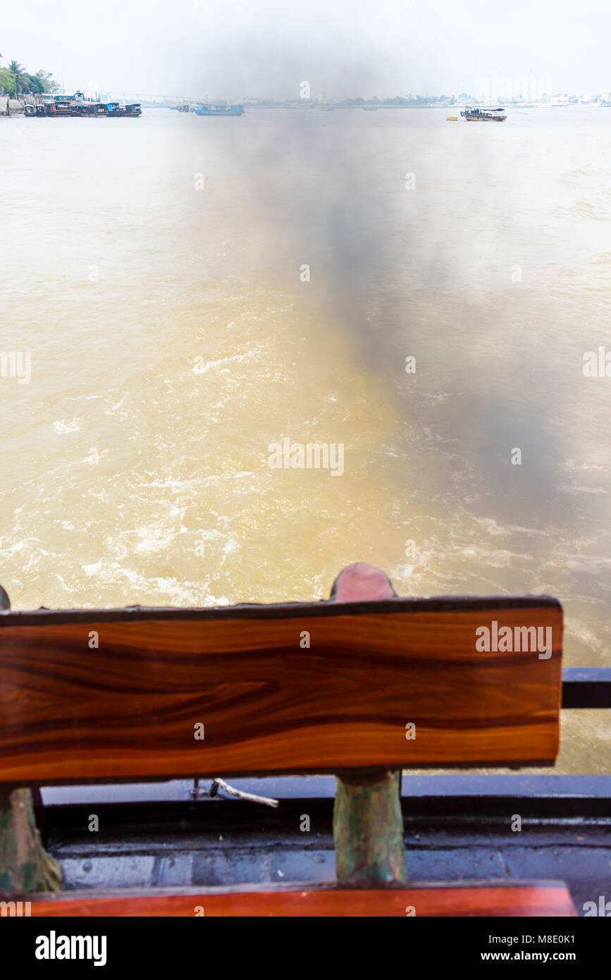 Dense, black smoke pours from the back of a tourist boat on the Meekong River, Vietnam Stock Photo