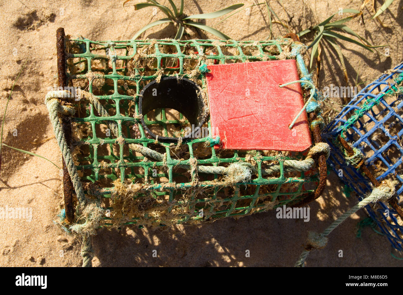 Close up of an old and worn-out, artisanal, crab trap made of iron and colored plastic materials. Vila Nova de Milfontes, Portugal. Stock Photo