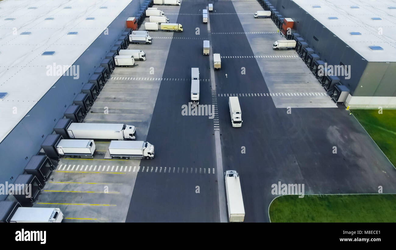 Aerial Shot of Industrial Warehouse/ Storage Building/ Loading Area where Many Trucks Are Loading/ Unloading Merchandise. Stock Photo