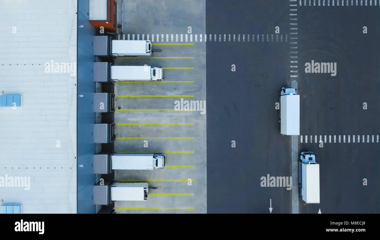 Aerial Shot of Truck with Attached Semi Trailer Leaving Industrial Warehouse/ Storage Building/ Loading Area where Many Trucks Are Load/ Unload Mercha Stock Photo