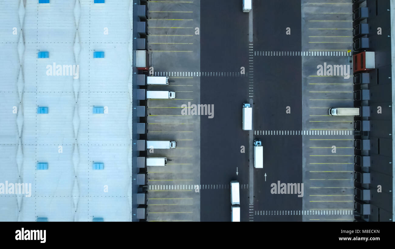 Aerial Shot of Industrial Warehouse/ Storage Building/ Loading Area where Many Trucks Are Loading/ Unloading Merchandise. Stock Photo