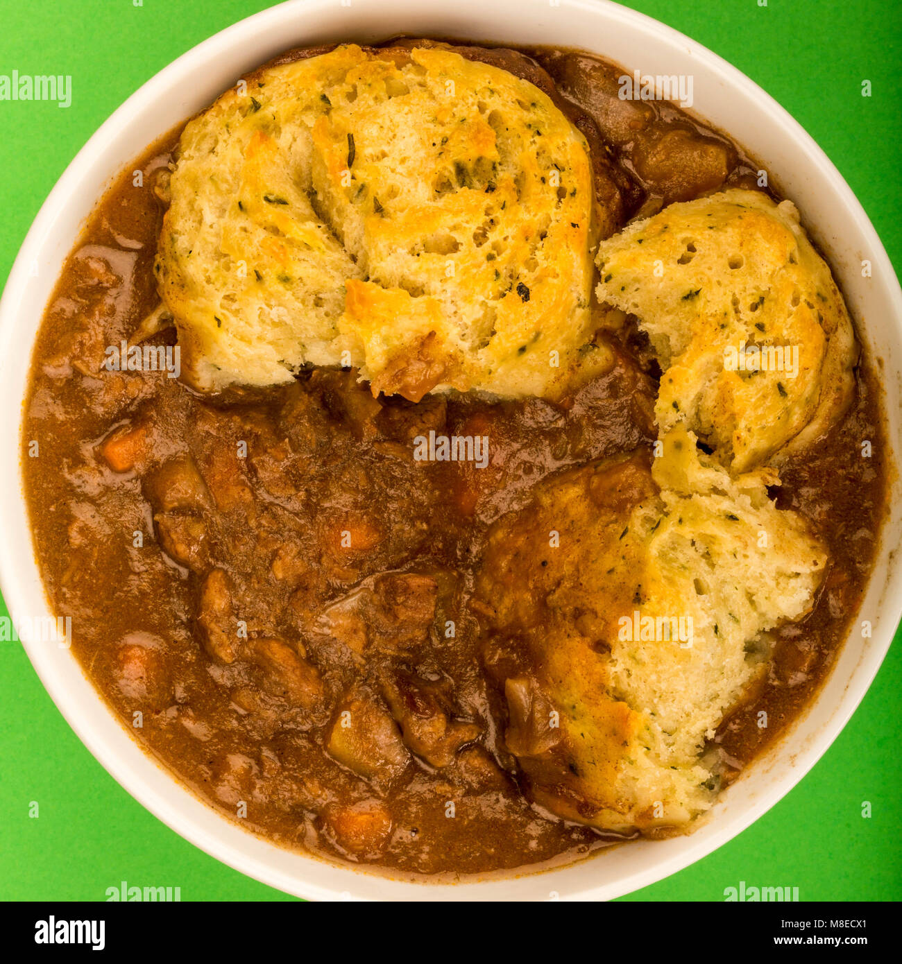 Traditional British Beef Casserole With Dumplings Against A Green Background Stock Photo
