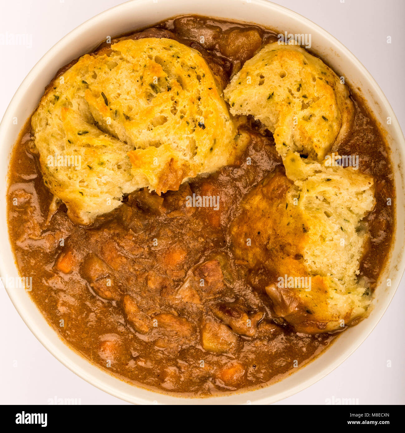Traditional British Beef Casserole With Dumplings Against A Pale Blue Background Stock Photo