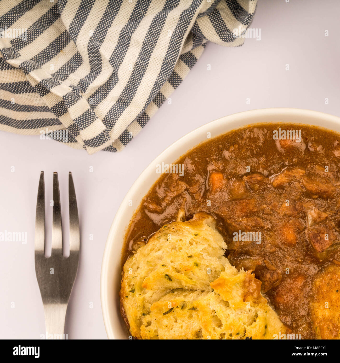 Traditional British Beef Casserole With Dumplings Against A Pale Blue Background Stock Photo