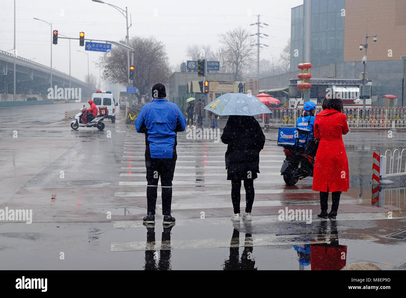 Beijing, China, March 17, 2018. Rare Snowy Day in Chaoyang District, Beijing, China. People crossing a street on a snowy day. Credit: Steven Liveoak/Alamy Live News Stock Photo
