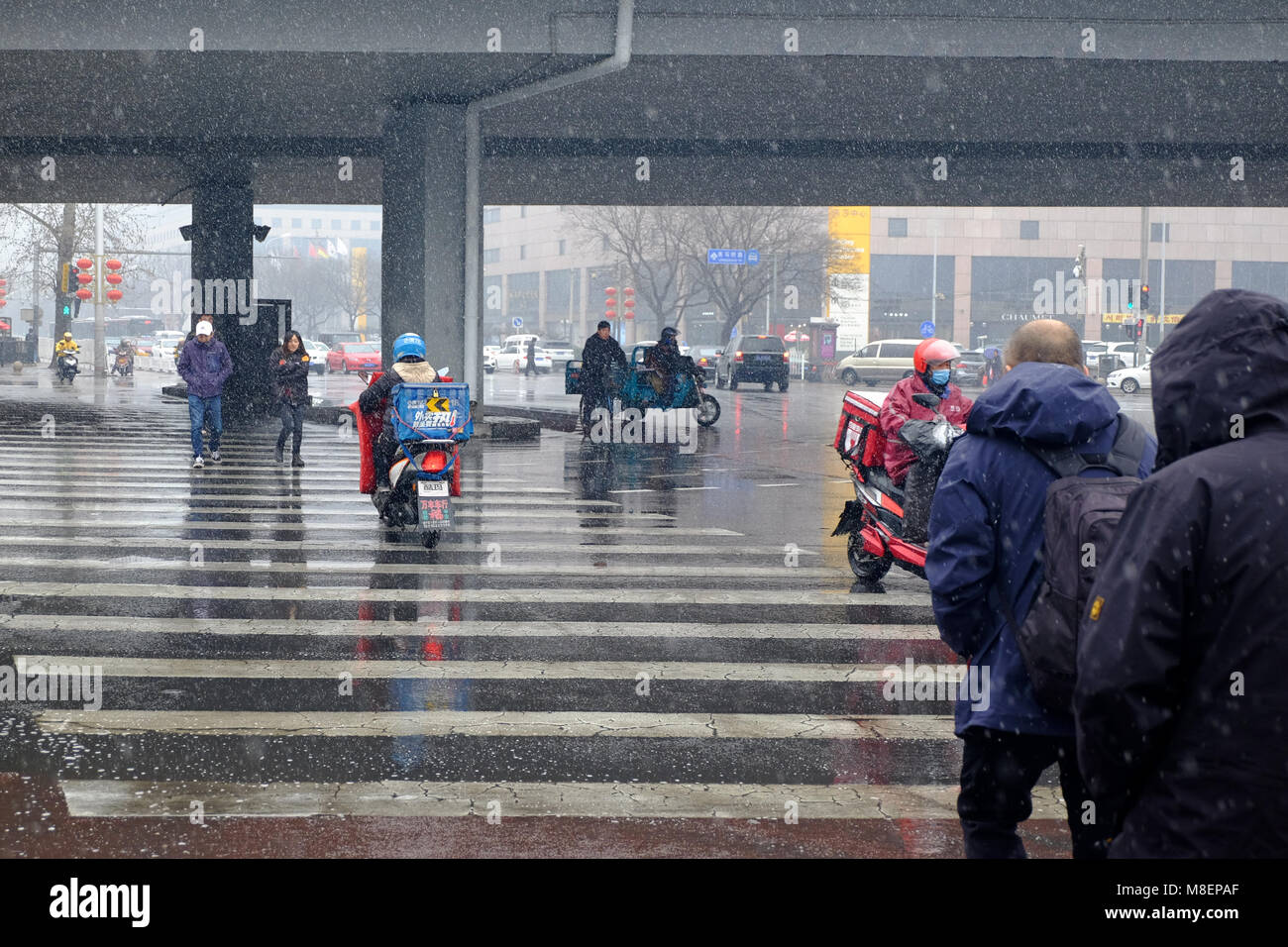 Beijing, China, March 17, 2018. Rare Snowy Day in Chaoyang District Beijing, China. People crossing a street on a snowy day. Credit: Steven Liveoak/Alamy Live News Stock Photo