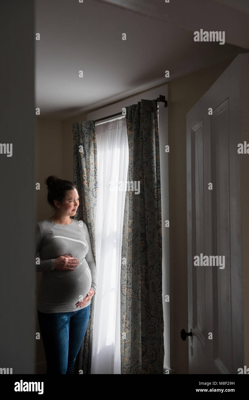 Pregnant woman looking through window Stock Photo Alamy