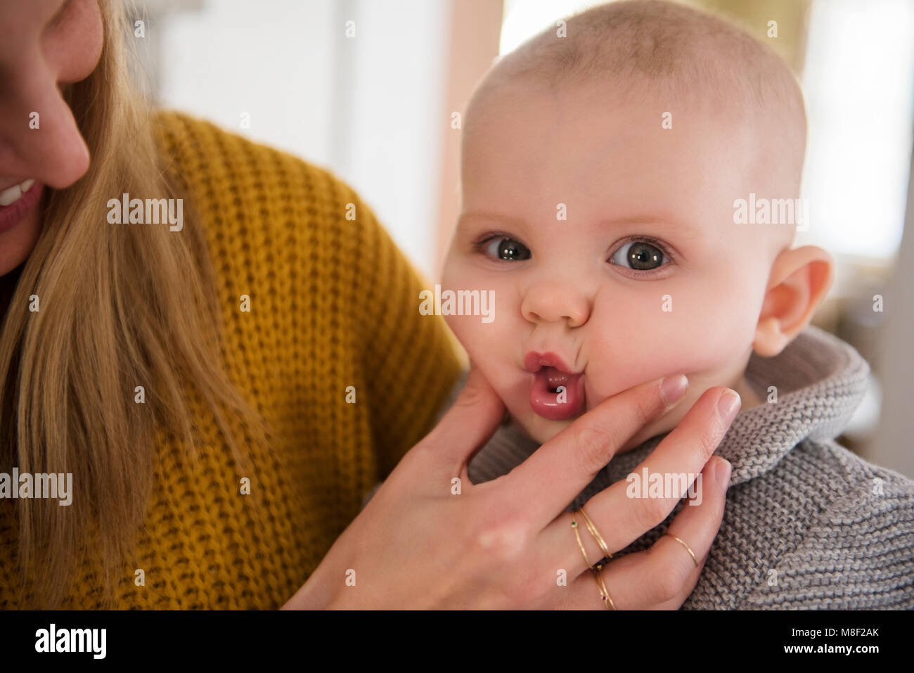 Mother squeezing baby's (12-17 months) face Stock Photo