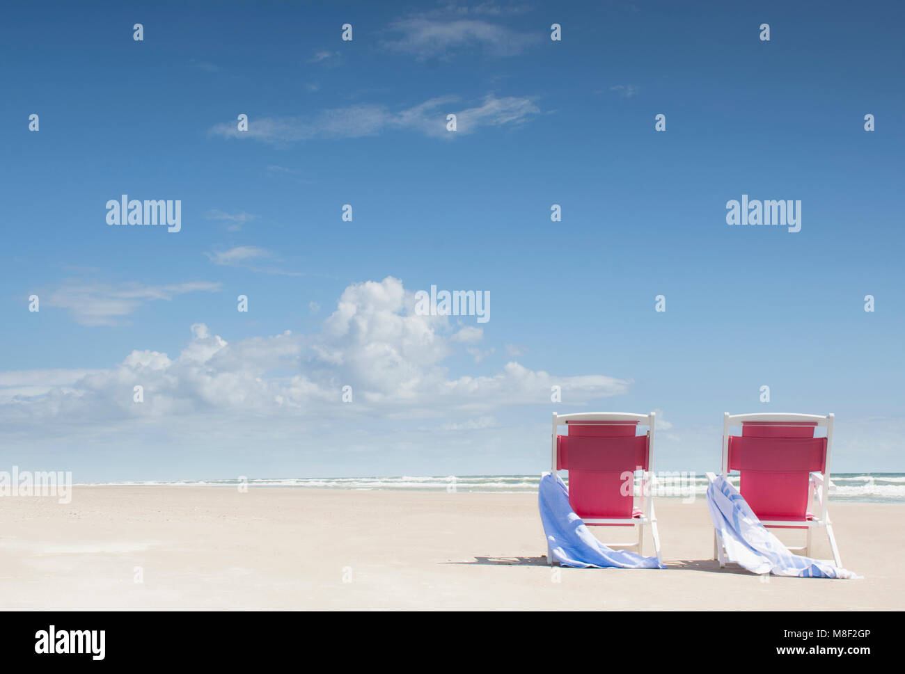 Deck chairs with towels on sandy beach by Atlantic Ocean Stock Photo