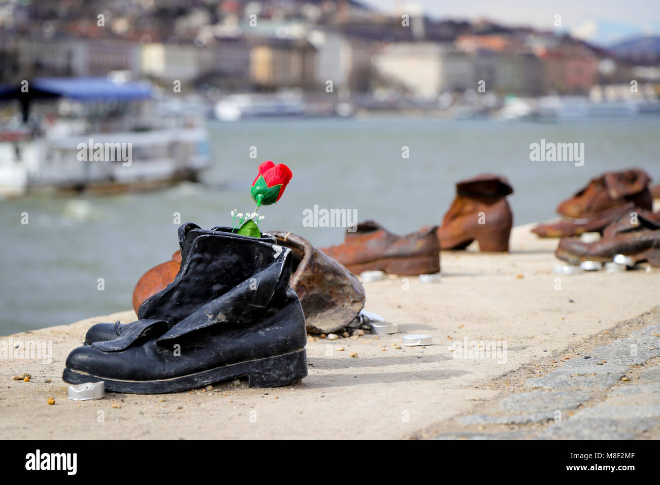 A solitary flower is left at the memorial sculpture 'The Shoes on the Danube Promenade', in remembrance of the Hungarian Jews who were executed there. Stock Photo