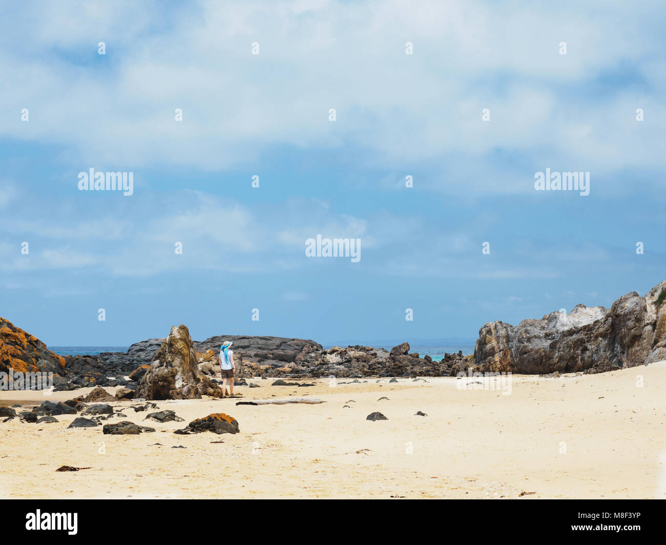 Australia, New South Wales, Bermagui, Woman walking along sandy beach Stock Photo