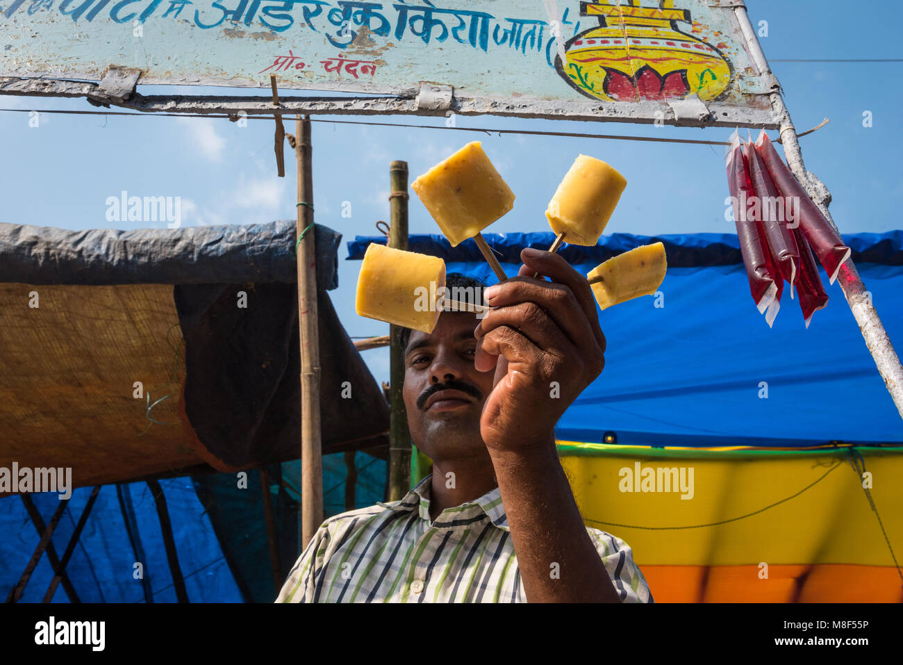 A man displaying the fruit-flavored ice that he is selling at the Sonepur Mela, Sonepur, India. Stock Photo