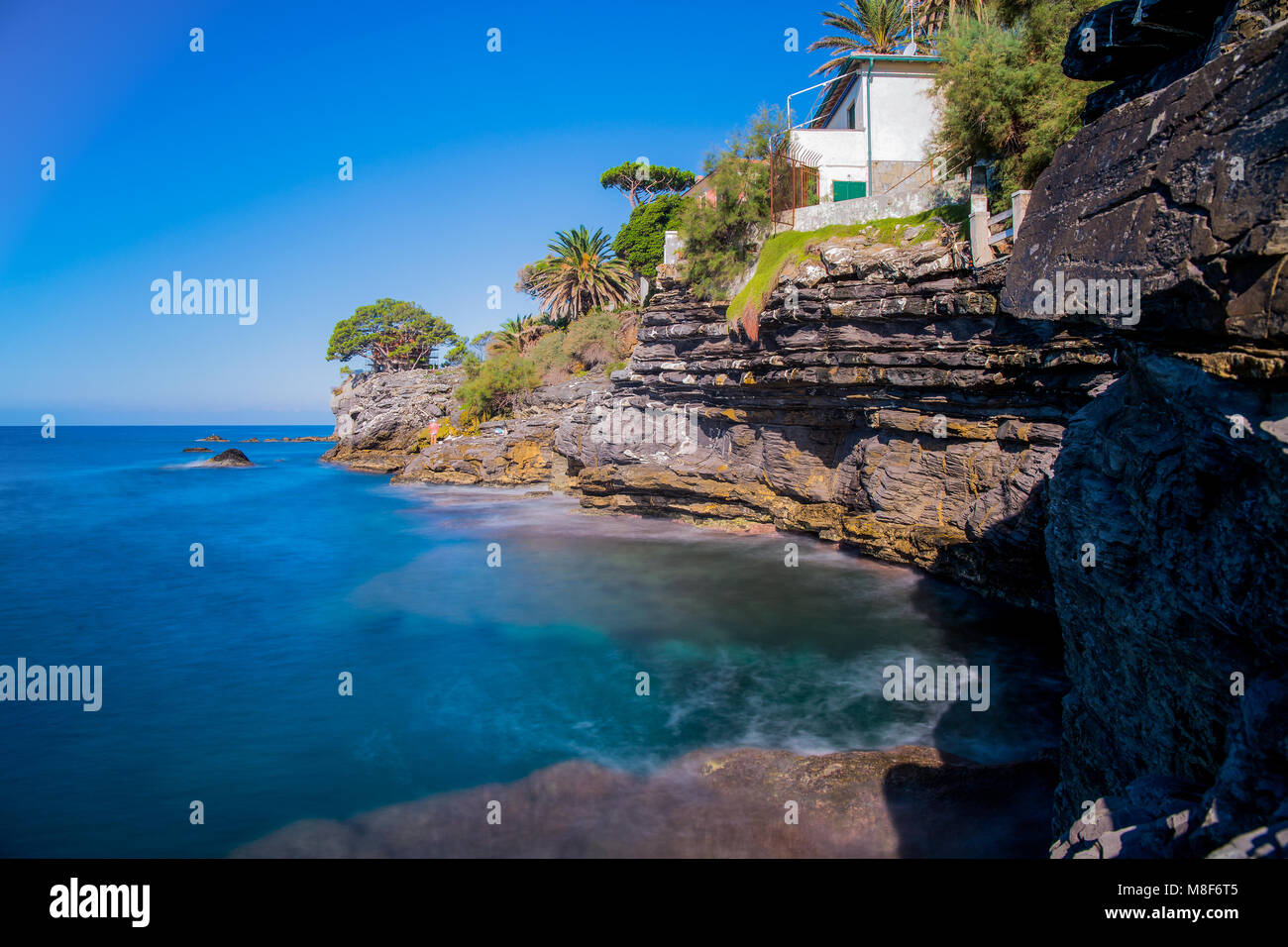 Long exposure seascape in a beautiful sunny day in summertime/ sea view/ blue sea/ green sea/ cliffs/ white house Stock Photo