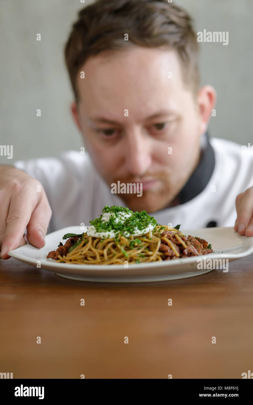 Chef in in a restaurant or hotel kitchen, checking up his food and ready for service to the customer Stock Photo