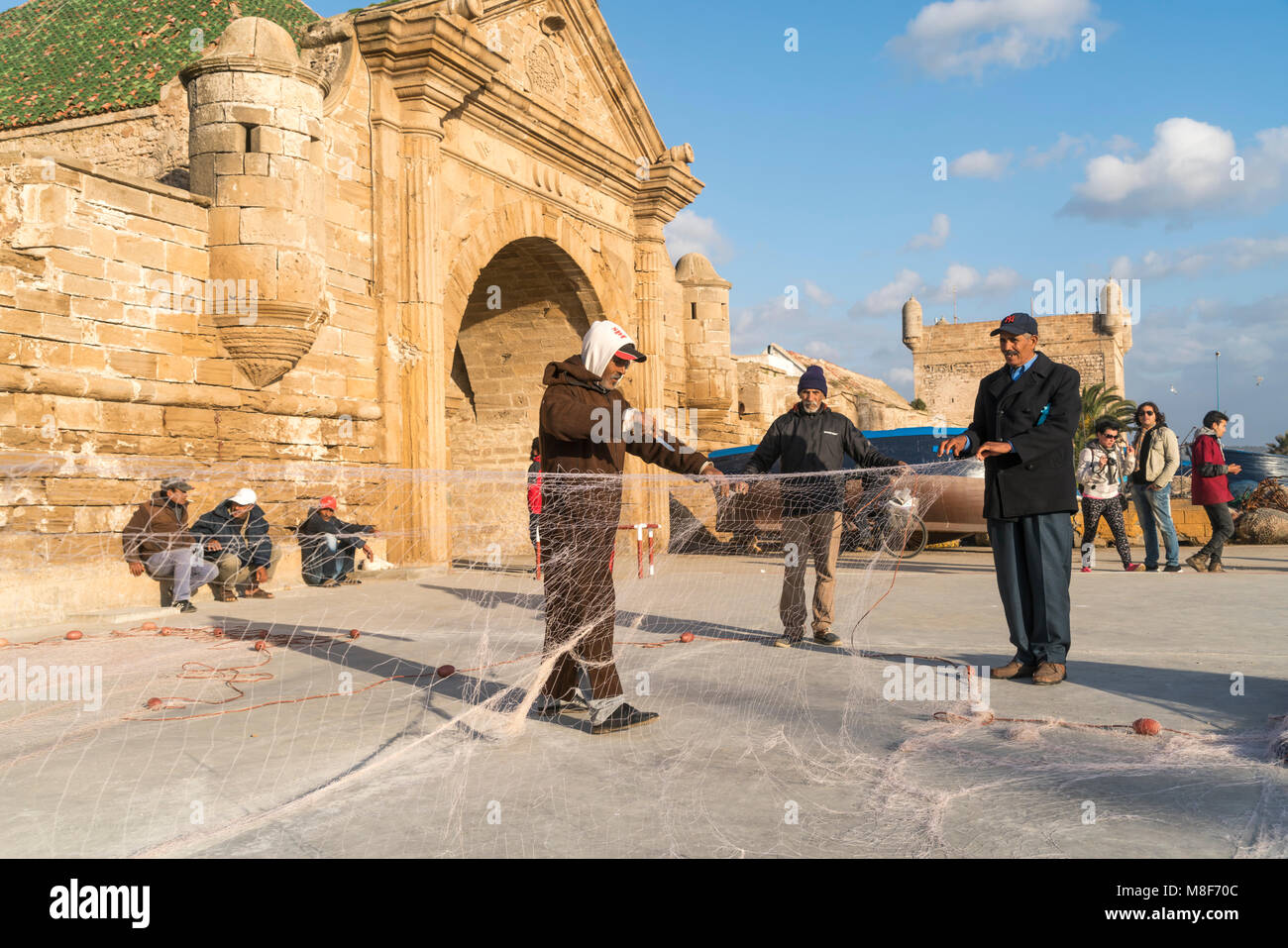 Fischer beim reparieren ohrer Netzte am Hafentor Porte de la Marine von Essaouira, Königreich Marokko, Afrika  |  fishermen repairing their nets at th Stock Photo